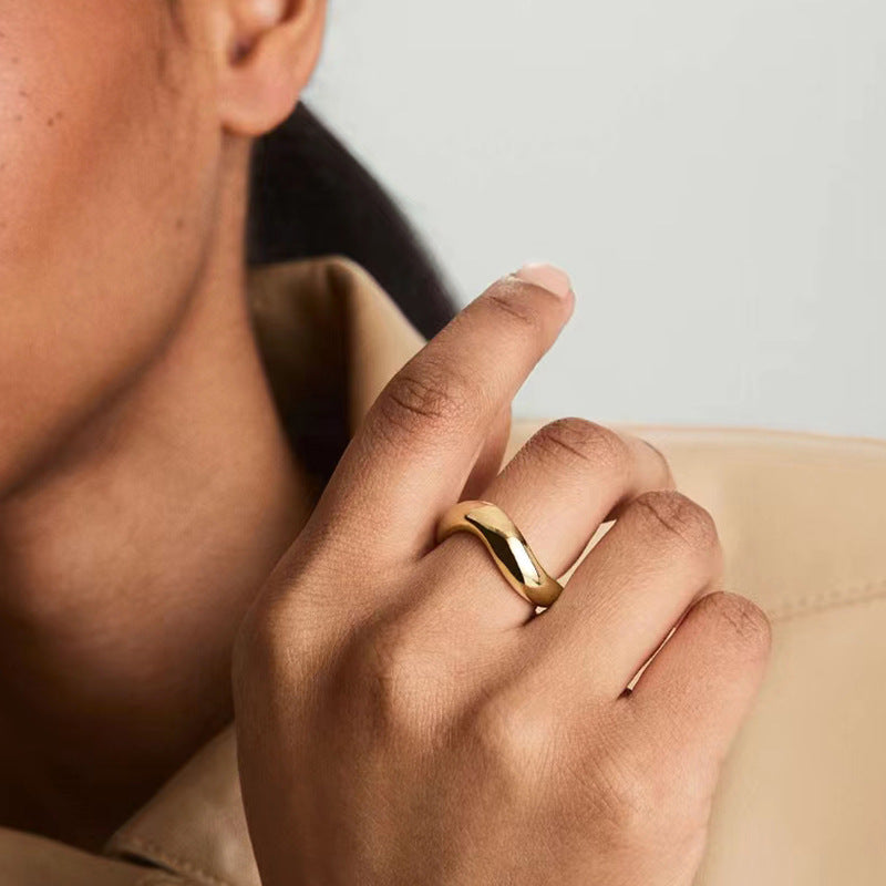 Curved gold band ring on woman's finger — PURAJOIA